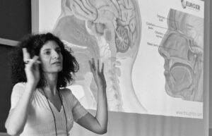 Ema presenting to a classroom in front of a screen showing a cross section of a human head with EUROXR logo in top right corner