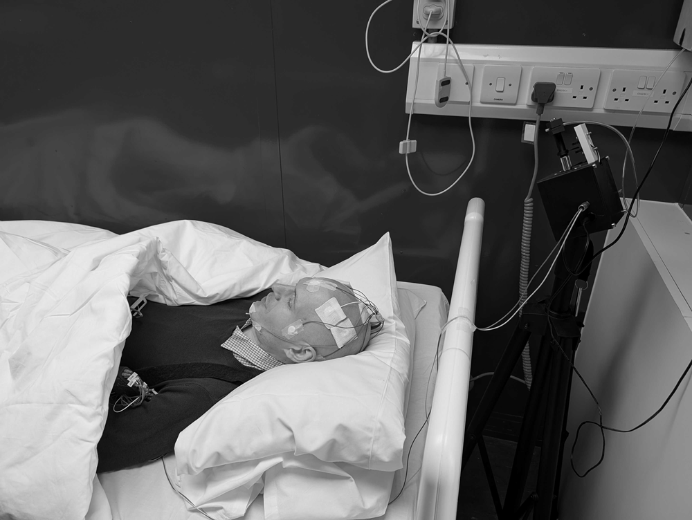A participant of Hynt's sleep study lying in bed with electrodes attached to their head